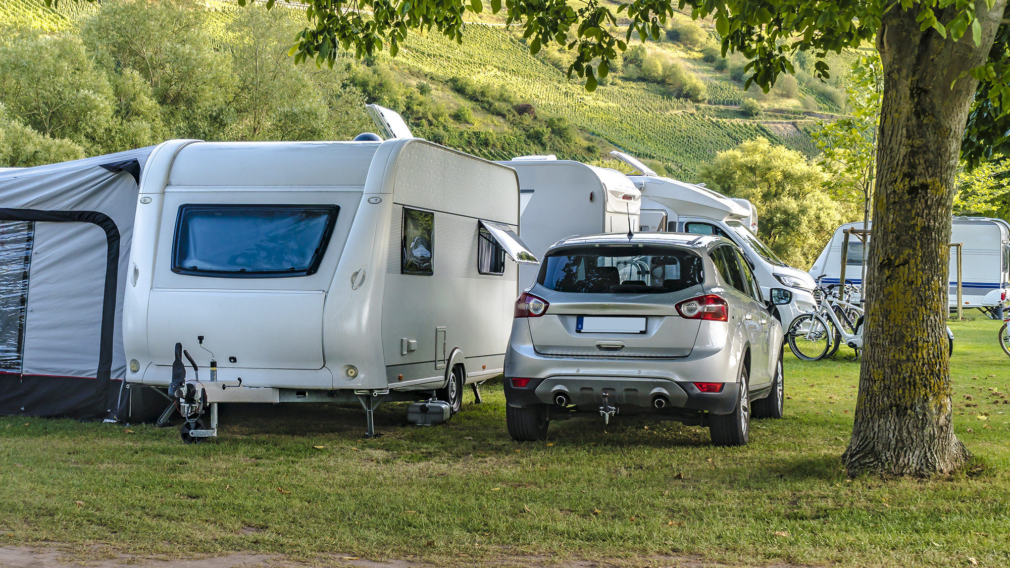 Caravan with awning attached next to a car in the French countryside
